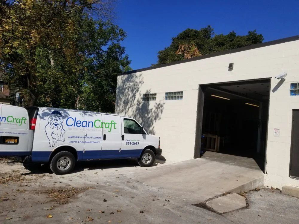 CleanCraft service van parked outside white building with open garage door