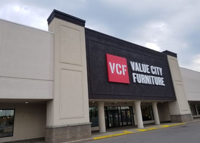 Value City Furniture storefront with red VCF logo and signage on dark exterior wall