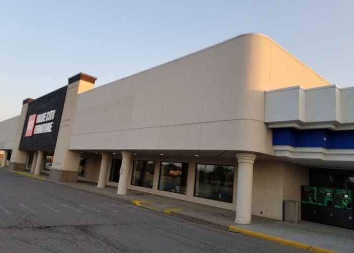 Exterior of a retail furniture store with beige facade and large storefront windows at dusk