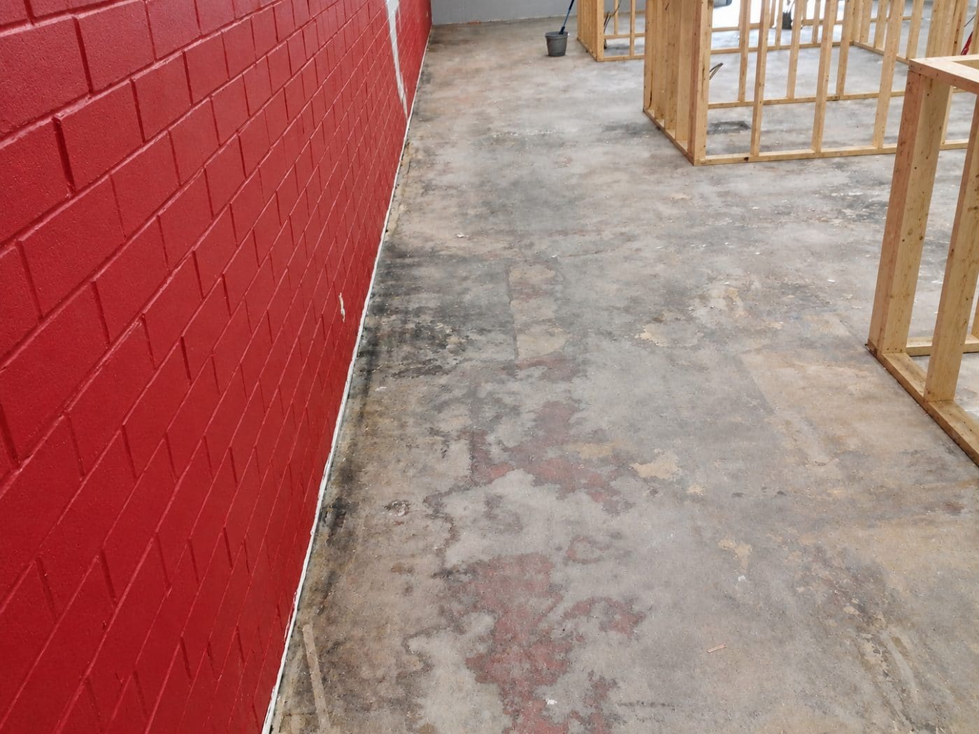 Interior space with red tiled wall, concrete floor, and wooden framed structures
