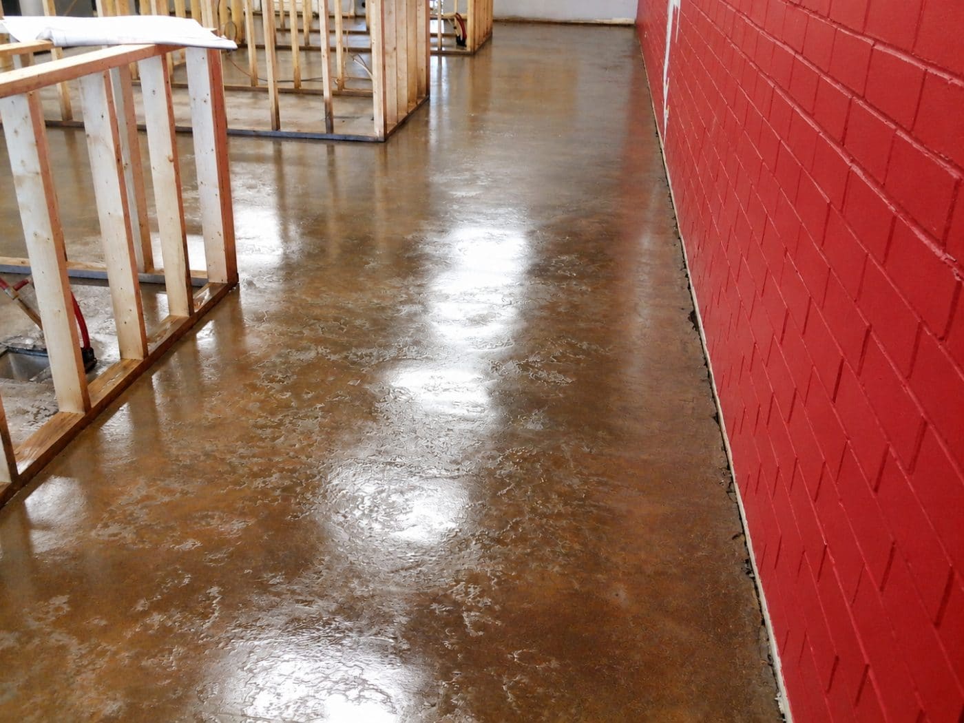 Polished concrete floor in industrial space with red brick wall and wooden framing structures