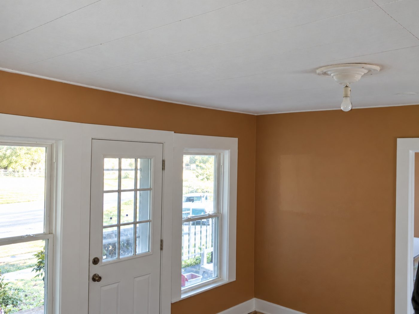 Interior room with tan walls, white ceiling, glass door and windows overlooking deck and landscape