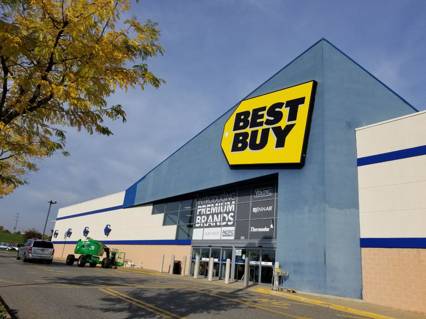 Best Buy storefront with yellow logo sign and blue striped exterior on autumn day
